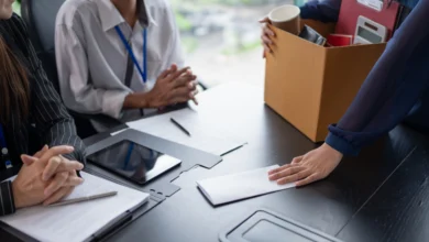 Ofis masasına zarf uzatan ve kişisel eşya kolisi tutan çalışan.